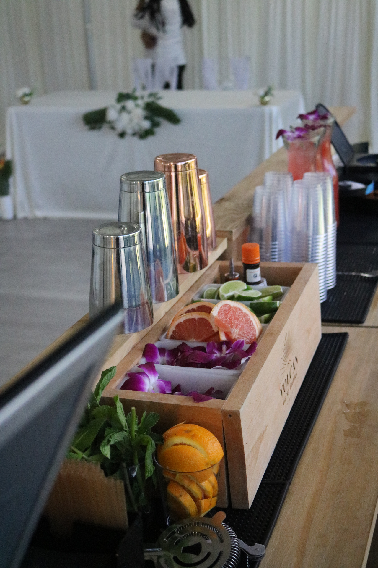 Garnish station with citrus, mint and orchids set up on the mobile bar at a wedding