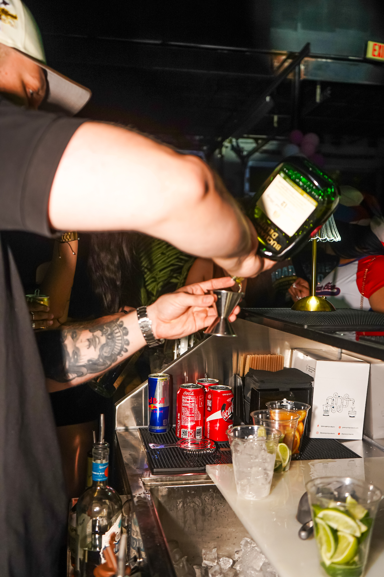 Bartender measuring a pour into a jigger behind the Dos Santos bar